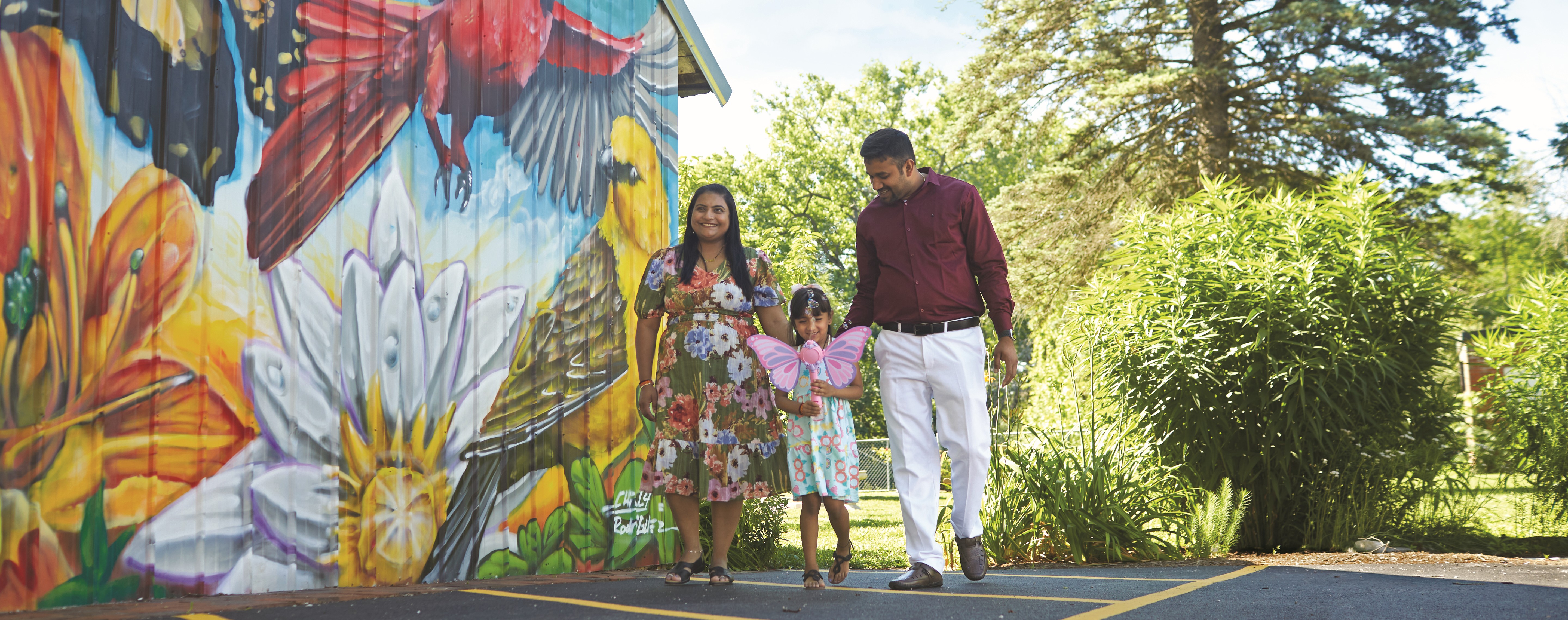 Family walking next to a mural wall with artwork on it.
